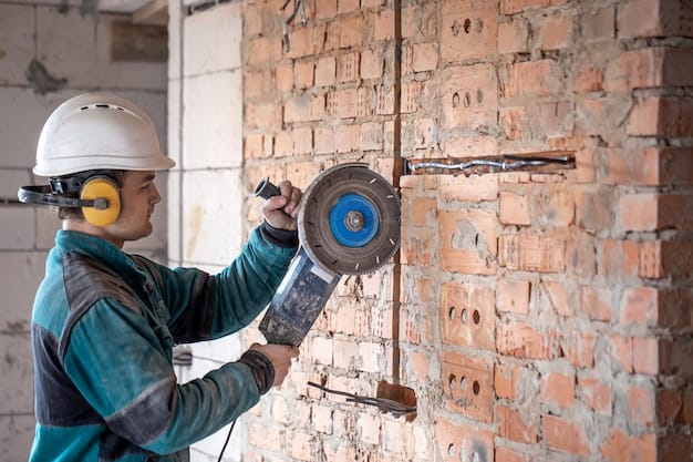 A professional builder in work clothes works with a cutting tool.